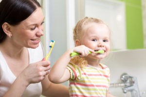 mother and child brushing their teeth together