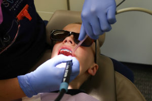 Young boy with braces getting a cavity treatment at a dental office